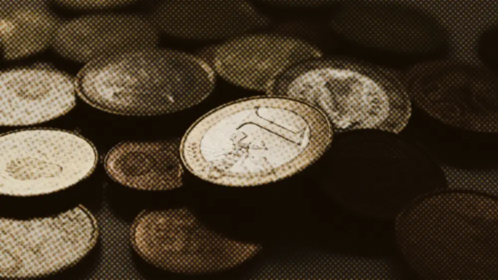 A spread of mixed euro coins across a dark table, a one-euro coin sharp in the middle of the scatter