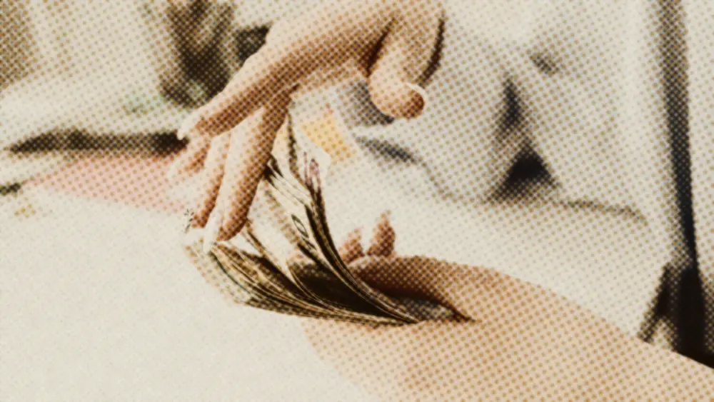 Close-up of a person's hands counting a fan of euro banknotes over a desk