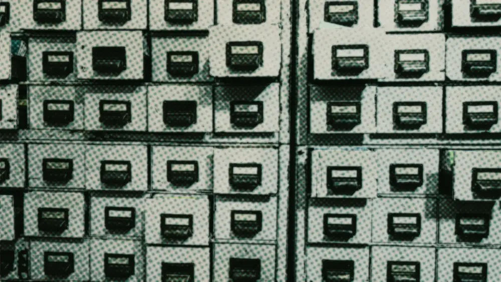 Rows of worn metal filing-cabinet drawers with blank label holders, several pulled slightly open